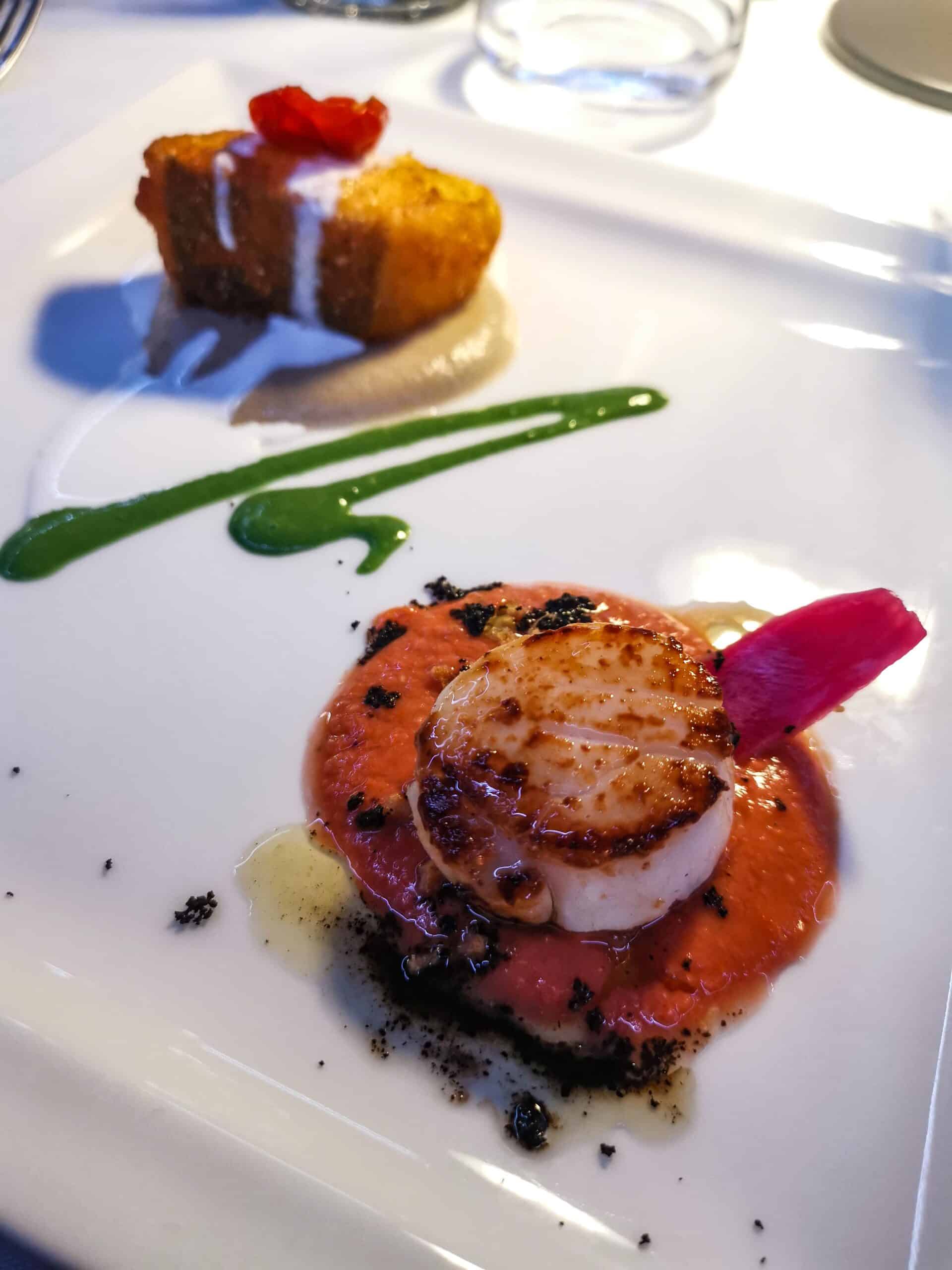 Capasanta con guazzetto di pomodoro, polvere di olive e cipolla croccante Capasanta con guazzetto di pomodoro, polvere di olive e cipolla croccante